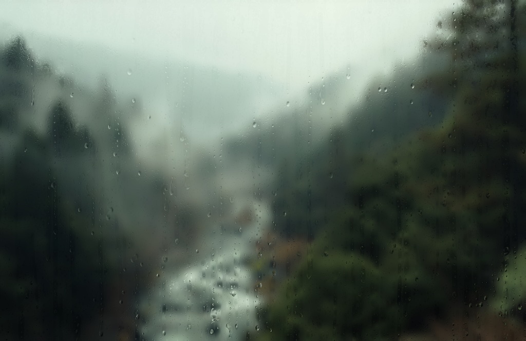 screen capture from within the Rainy Day screensaver: a stream running through a wooded mountain valley, with mist and raindrops